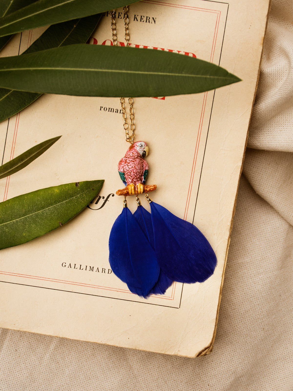 collier doré perroquet rose bleu plume bleue